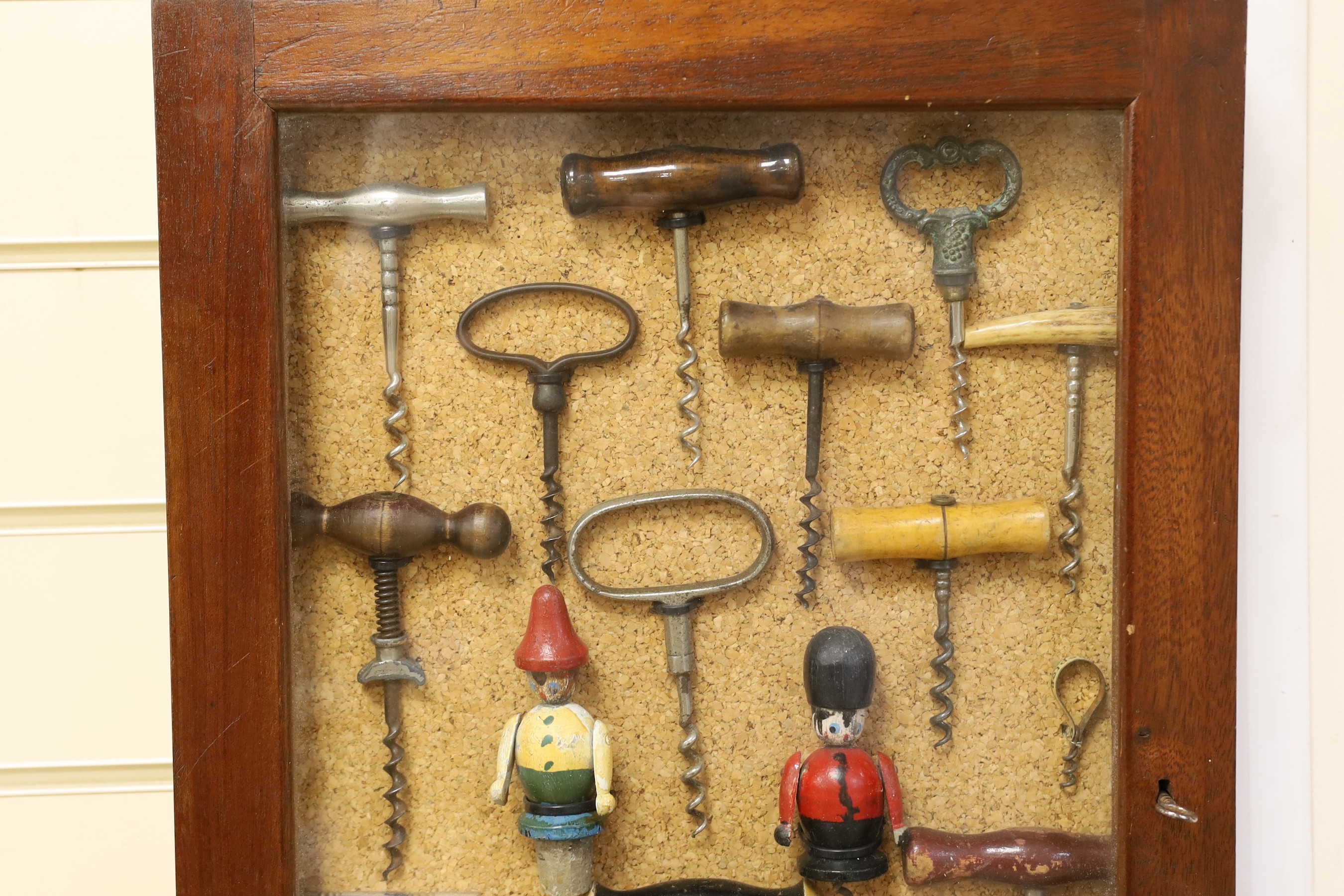 A collection of vintage corkscrews, some novelty, in glazed mahogany vase with key